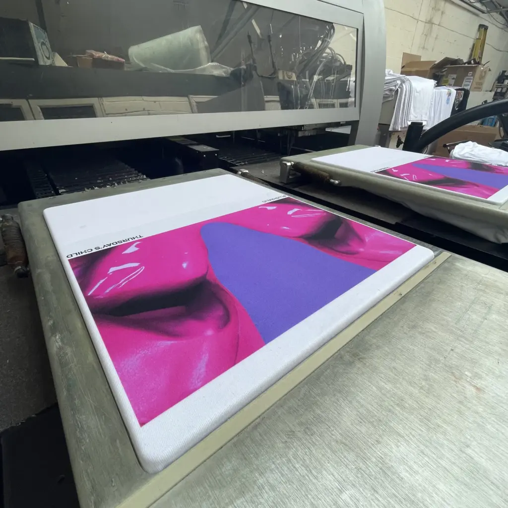 a vibrant pink and purple design printed on a white t-shirt that is loaded onto a direct to garment (dtg) machine.